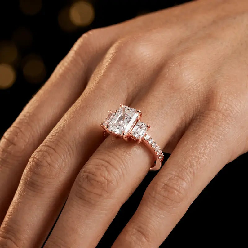 Radiant cut three-stone lab-grown diamond engagement ring in 18kt rose gold with diamond shoulders worn on hand