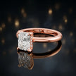 Angled view of 4-claw radiant cut engagement ring with hidden halo in 18kt rose gold