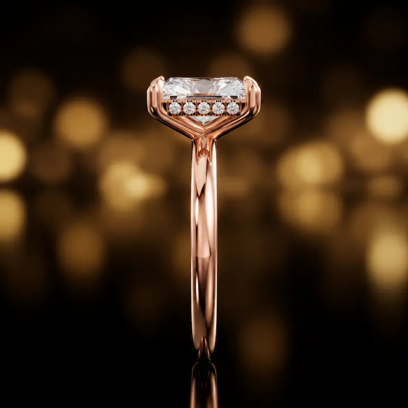 Side profile of 4-claw radiant cut engagement ring with hidden halo in 18kt rose gold
