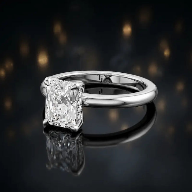 Angled view of 4-claw radiant cut engagement ring with hidden halo in 18kt white gold