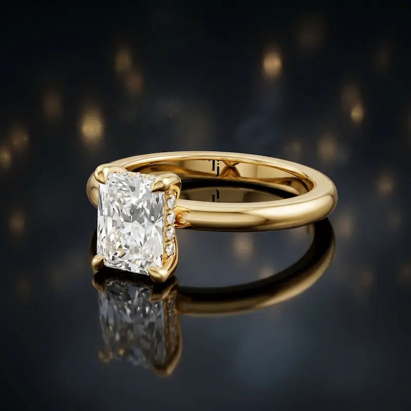 Angled view of 4-claw radiant cut engagement ring with hidden halo in 18kt yellow gold