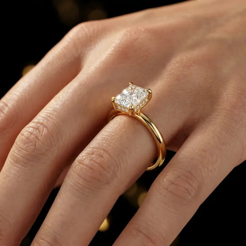 4-claw radiant cut engagement ring with hidden halo in 18kt yellow gold, worn on hand