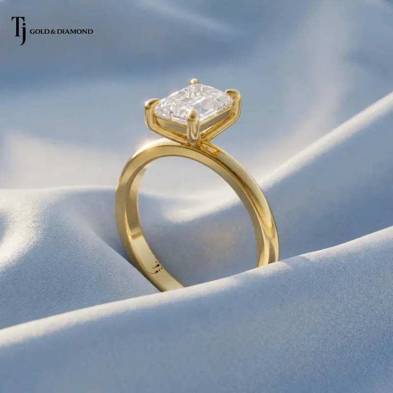 1.5 carat radiant cut lab-grown diamond solitaire engagement ring in 18kt yellow gold with a 4-claw setting, angled view on pink silk
