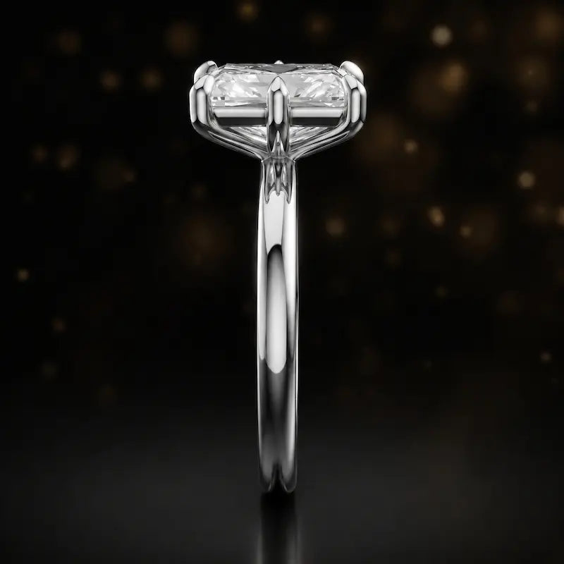 Side profile of a 1.5 carat radiant cut diamond solitaire engagement ring showing the cathedral setting and 18kt white gold band by TJ Diamond