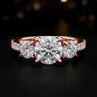 Front view of a round cut three-stone lab-grown diamond engagement ring in 18kt rose gold with diamond shoulders