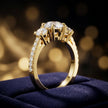 Angled view of a round cut three-stone lab-grown diamond engagement ring in 18kt yellow gold with diamond shoulders