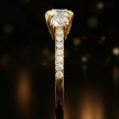 Side profile of a round cut three-stone lab-grown diamond engagement ring in 18kt yellow gold showing the diamond band