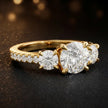 Side view of a round cut three-stone lab-grown diamond engagement ring in 18kt yellow gold with diamond shoulders