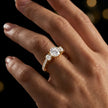 Round cut three-stone lab-grown diamond engagement ring in 18kt yellow gold with diamond shoulders worn on hand