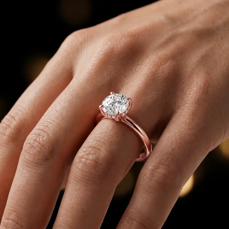 4-claw round cut engagement ring with hidden halo in 18kt rose gold, worn on hand