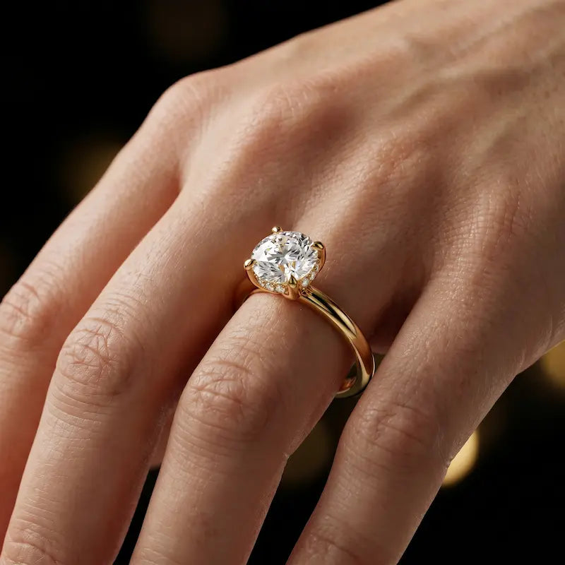 4-claw round cut engagement ring with hidden halo in 18kt yellow gold, worn on hand