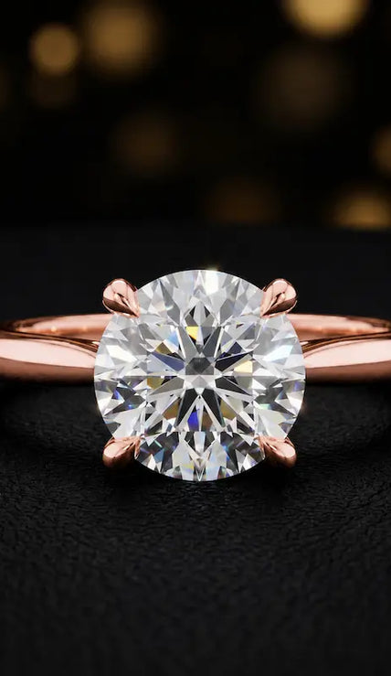 Front view of a 1.5 carat round brilliant cut diamond solitaire engagement ring in an 18kt rose gold 4 claw setting by TJ Diamond