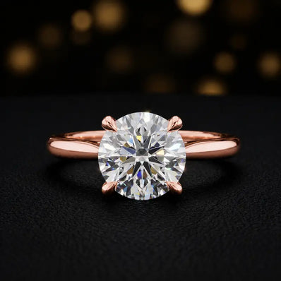Front view of a 1.5 carat round brilliant cut diamond solitaire engagement ring in an 18kt rose gold 4 claw setting by TJ Diamond