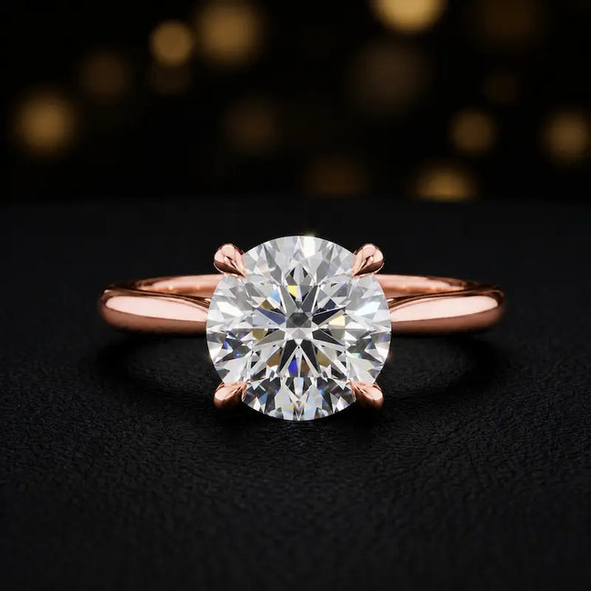 Front view of a 1.5 carat round brilliant cut diamond solitaire engagement ring in an 18kt rose gold 4 claw setting by TJ Diamond