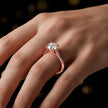 Round brilliant cut diamond solitaire engagement ring in an 18kt rose gold 4 claw setting worn on a hand, by TJ Diamond