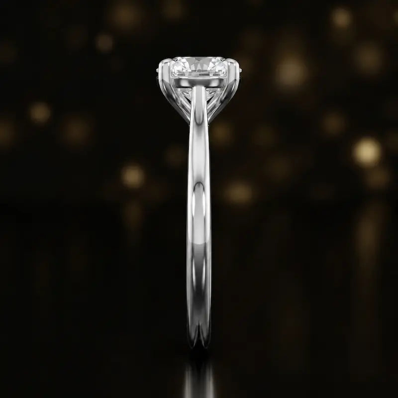 Side profile of a 1.5 carat round brilliant cut diamond solitaire engagement ring showing the cathedral setting and 18kt white gold band by TJ Diamond