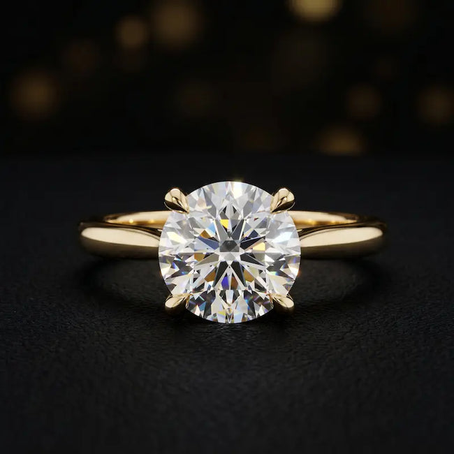 Front view of a 1.5 carat round brilliant cut diamond solitaire engagement ring in an 18kt yellow gold 4 claw setting by TJ Diamond