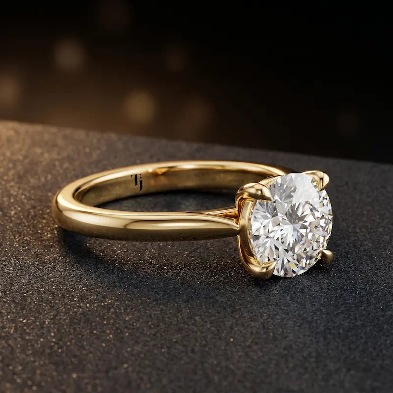 Angled side view of a 1.5 carat round brilliant cut diamond solitaire engagement ring in an 18kt yellow gold 4 claw setting by TJ Diamond