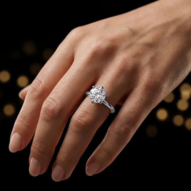 1.5 carat round brilliant cut diamond solitaire engagement ring in an 18kt white gold 6 claw setting worn on a hand, by TJ Diamond