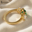 Top View of a round cut lab-created emerald trilogy engagement ring in 18kt yellow gold with round brilliant lab-grown diamond side stones.