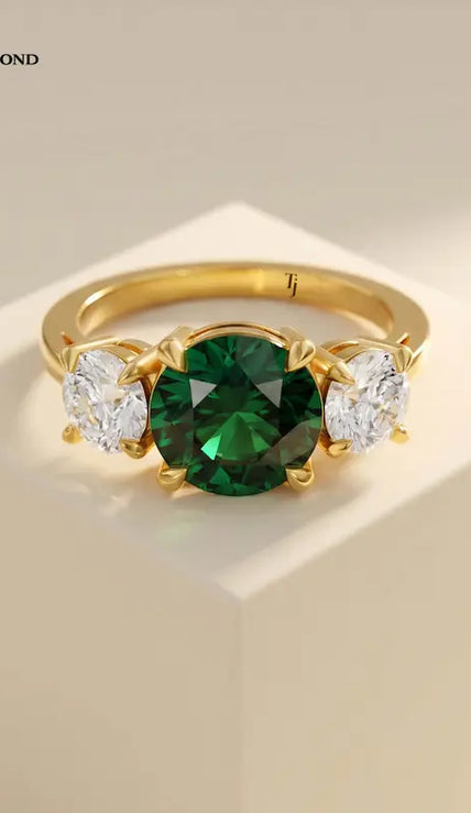 Front View of a round cut lab-created emerald trilogy engagement ring in 18kt yellow gold with round brilliant lab-grown diamond side stones.