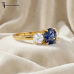 Angled close-up of a Round Cut Lab-Created Blue Sapphire & Lab-Grown Diamond Trilogy Ring in polished 18kt yellow gold.