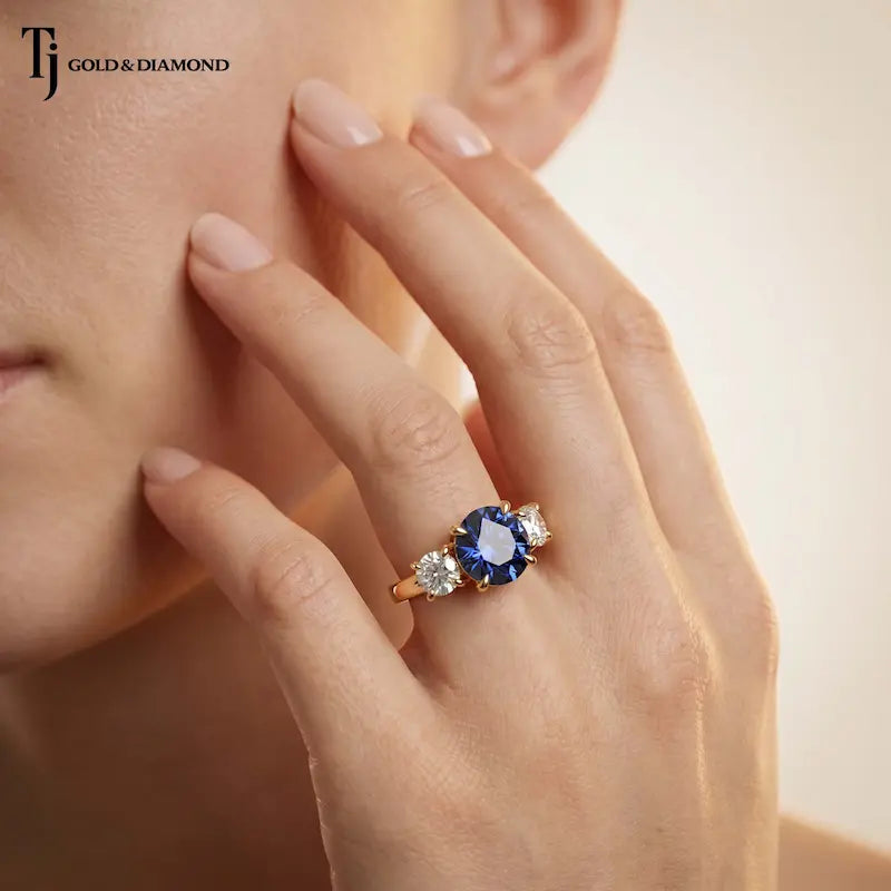 Model wearing a Round Cut Lab-Created Blue Sapphire & Lab-Grown Diamond Trilogy Ring handcrafted in 18kt yellow gold.