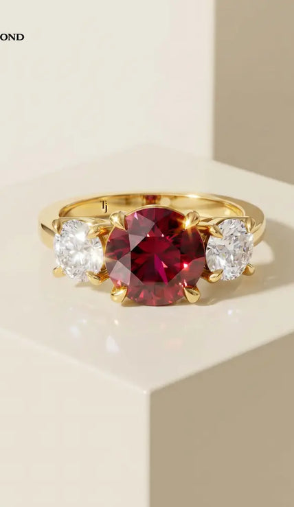 Front view of a round brilliant lab-created ruby trilogy engagement ring in 18kt yellow gold with round brilliant lab-grown diamond side stones.