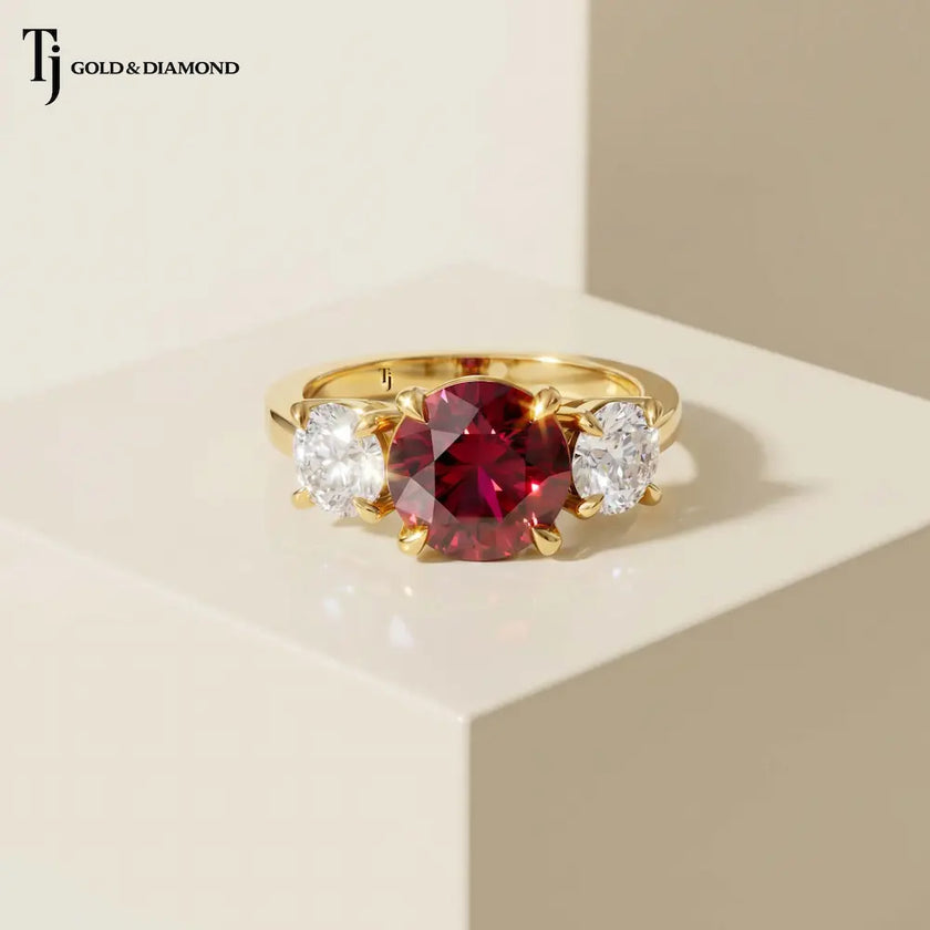 Front view of a round brilliant lab-created ruby trilogy engagement ring in 18kt yellow gold with round brilliant lab-grown diamond side stones.