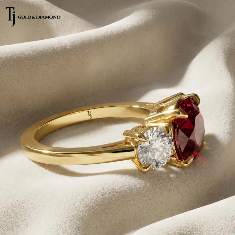 Side profile of a round brilliant lab-created ruby trilogy engagement ring in 18kt yellow gold with round brilliant lab-grown diamond side stones and a four claw basket setting.