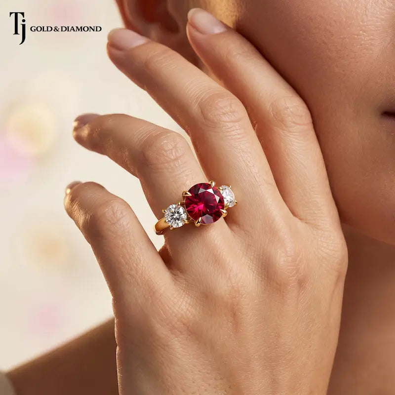Model wearing a round brilliant lab-created ruby trilogy engagement ring in 18kt yellow gold with round brilliant lab-grown diamond side stones.