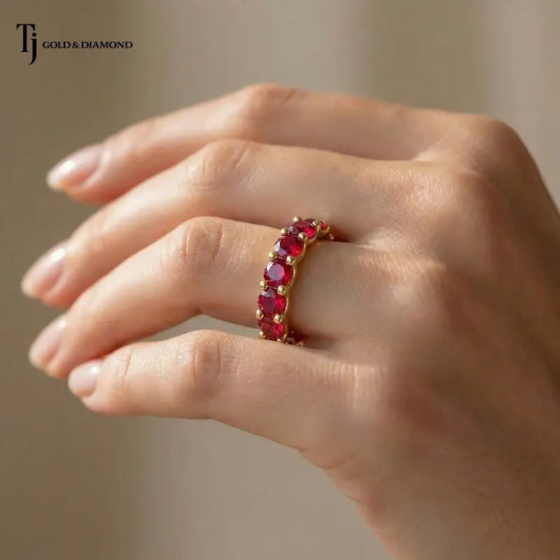 Created ruby full eternity ring in 18kt yellow gold worn on hand with round brilliant lab-created rubies.