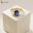 Created emerald cut sapphire and diamond trilogy ring in 18kt yellow gold featuring a vibrant blue lab-created sapphire with emerald cut lab-grown diamond side stones