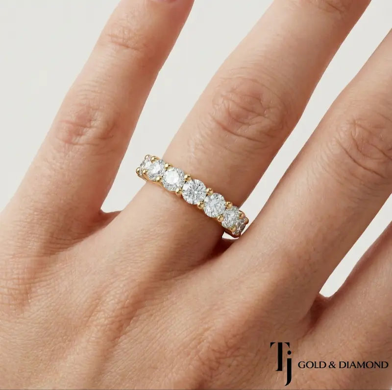 Shared prong setting full eternity diamond wedding band in 18kt yellow gold worn on hand with round brilliant lab-grown diamonds.