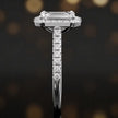 Side profile of an emerald cut halo lab-grown diamond engagement ring with diamond-set shoulders in 18kt white gold.