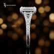 Side profile of an emerald cut split shank lab-grown diamond engagement ring with diamond-set shoulders in 18kt white gold.