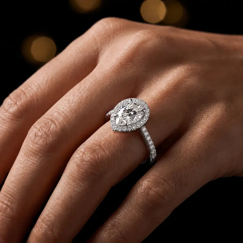 Pear cut halo lab-grown diamond engagement ring worn on hand in 18kt white gold.