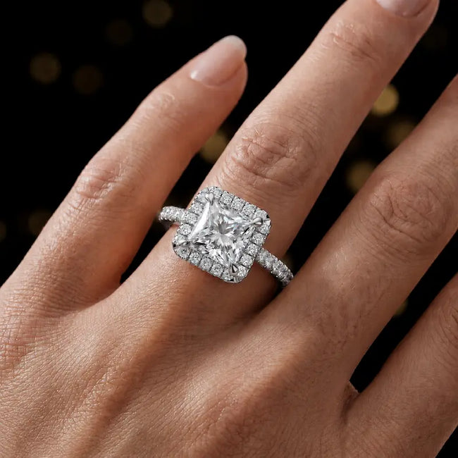 Princess cut halo lab-grown diamond engagement ring worn on hand in 18kt white gold.