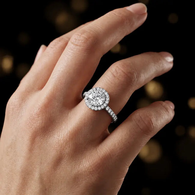 Round cut halo lab-grown diamond engagement ring worn on hand in 18kt white gold.