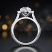 Side view of a round cut halo lab-grown diamond engagement ring with diamond-set shoulders in 18kt white gold.