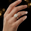 Emerald cut halo lab-grown diamond engagement ring worn on hand in 18kt yellow gold.