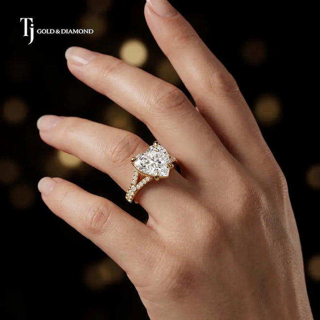 Heart cut split shank lab-grown diamond engagement ring worn on hand in 18kt yellow gold.