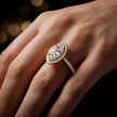 Marquise cut halo lab-grown diamond engagement ring worn on hand in 18kt yellow gold.