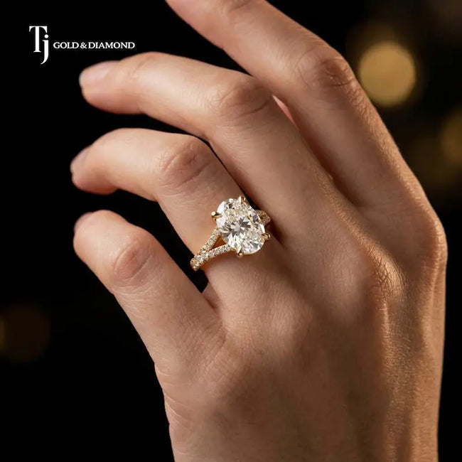 Oval cut split shank lab-grown diamond engagement ring worn on hand in 18kt yellow gold.