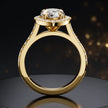 Side view of a pear cut halo lab-grown diamond engagement ring with diamond-set shoulders in 18kt yellow gold.