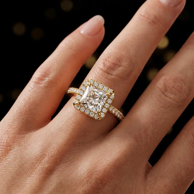 Princess cut halo lab-grown diamond engagement ring worn on hand in 18kt yellow gold.