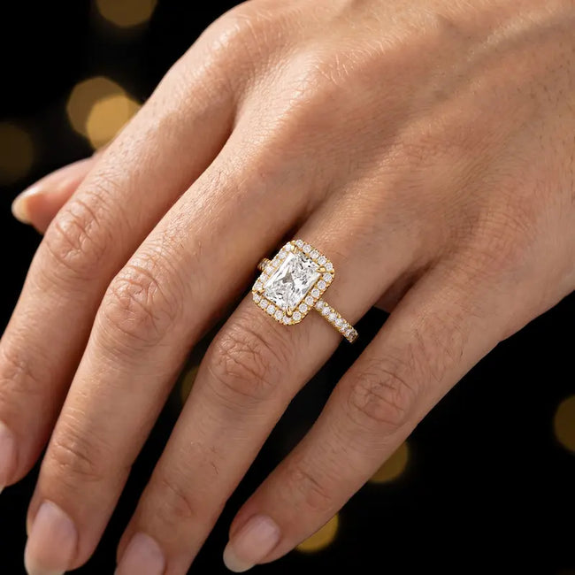 Radiant cut halo lab-grown diamond engagement ring worn on hand in 18kt yellow gold.