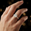 Round cut halo lab-grown diamond engagement ring worn on hand in 18kt yellow gold.