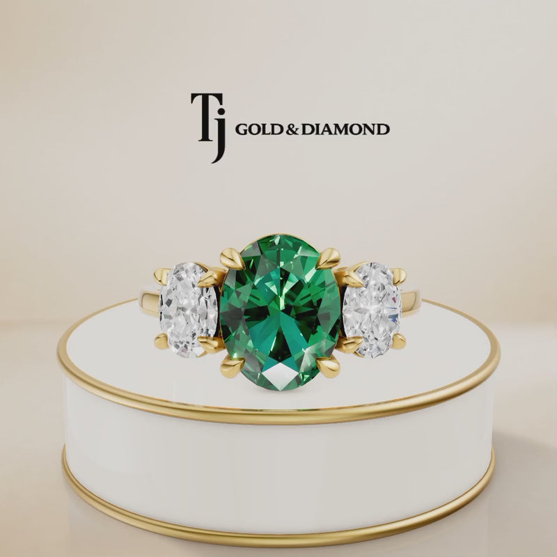 360° product view of an oval lab-created emerald trilogy engagement ring in 18kt yellow gold with oval lab-grown diamond side stones and a classic four claw basket setting.