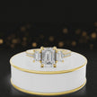 360-degree rotating view of an emerald cut three-stone lab-grown diamond engagement ring in 18kt yellow gold with diamond shoulders